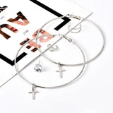 Boucles d'oreilles anneaux croix posé sur une table